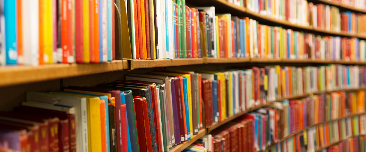 Photo of colorful books on a library shelf.